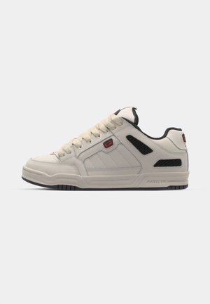 Sneaker in pelle bianca con accenti in mesh neri, punta arrotondata, suola spessa, cuciture a contrasto e logo prominente sul lato.