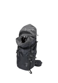 Zaino da trekking nero con spallacci regolabili, apertura superiore con coulisse e istruzioni stampate sul coperchio, marchiato Jack Wolfskin.