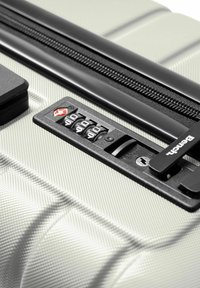 Valigia rigida argento con superficie testurizzata, cerniera nera, lucchetto a combinazione e foro di chiusura approvato TSA per viaggi sicuri.