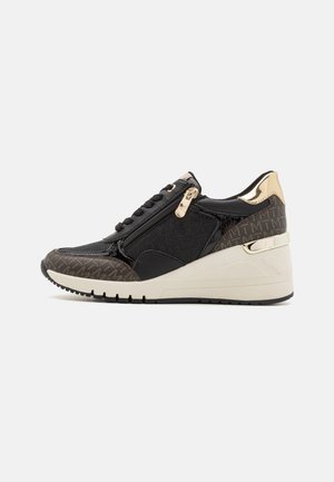 Black wedge sneaker with beige sole, gold zipper and heel accents, patterned toe and heel panels, and lace-up front.