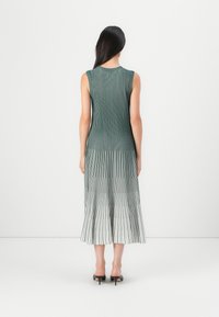 Green pleated dress with a fitted bodice, featuring vertical stripes that fade to white at the hem, designed with a sleeveless cut.