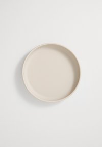 Round ceramic plate in a soft beige color, featuring a smooth, matte finish and slightly raised edges for added design detail.