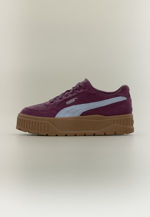 Σκούρο κόκκινο αθλητικό παπούτσι Puma με μπλε πλευρική λωρίδα και παχιά καφέ λαστιχένια σόλα, εμφανίζεται από το πλάι σε απλό φωτεινό φόντο.