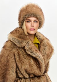 Cappotto in pelliccia sintetica con ampio colletto, in tonalità di marrone, caratterizzato da una vita con cintura. Abbinato a un cappello in pelliccia coordinato, completando il look.