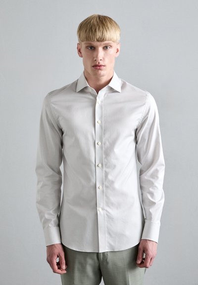Hvid langærmet skjorte med knapper lavet af bomuld. Har en krave, frontknapper og et slim fit-design. Glat tekstur; minimalistisk stil.