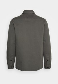 Donkergroene shirt, lange mouwen, knoopmanchetten en een rechte zoom. Gemaakt van een gestructureerde stof, met een standaard kraagontwerp.