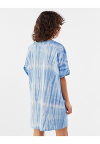 Modrá tie-dye oversized tričková šaty s krátkými rukávy, vyrobená z měkké, texturované látky a volného střihu; světle a tmavě modré vzory.