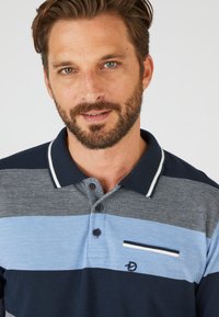 Polo con righe orizzontali in navy, azzurro e grigio; presenta una tasca, tre bottoni e un colletto a contrasto.
