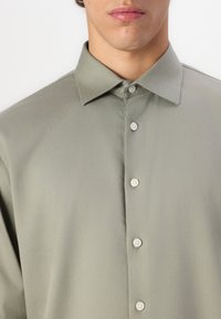 Chemise col jaune clair en tissu lisse avec un devant boutonné, dotée de boutons assortis et d'un design à coupe normale.