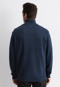 Dunkelblauer Wollpullover, gerippter Rollkragen, lange Ärmel, aus einem strukturierten Stoff mit Farbnuancen, abgerundet mit einem gerippten Saum und Bündchen.