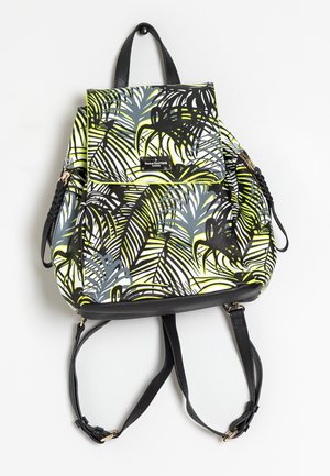 Mochila con estampado de hojas tropicales en negro, blanco, gris y amarillo, correas negras y solapa frontal con etiqueta de la marca.