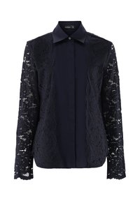 Navybluse mit klassischem Kragen, Knopfleiste und langen Spitzensäumen mit gewelltem Rand. Der glatte Stoff des Körpers kontrastiert mit der Spitzenstruktur.