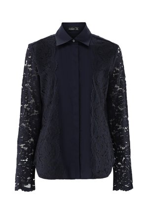 Navybluse mit klassischem Kragen, Knopfleiste und langen Spitzensäumen mit gewelltem Rand. Der glatte Stoff des Körpers kontrastiert mit der Spitzenstruktur.