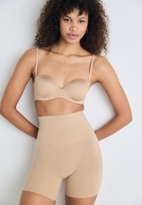 Set de lenjerie modelatoare bej, cu un sutien căptușit, neted și pantaloni scurți cu talie înaltă, realizat dintr-un material moale și elastic, cu un design fără cusături.