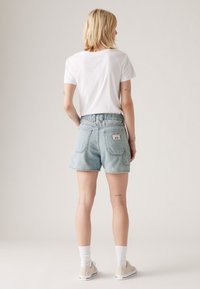 Fénykék denim rövidnadrág, laza szabással, hátoldalán egy zsebbel, puha fehér pólóval. Pamut keverék, laza stílus.