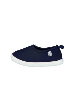 Zapato de color azul marino tipo slip-on con suela de goma blanca y pequeña etiqueta de marca en el lateral, diseñado para uso casual.