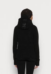Zwarte hoodie van zachte stof met een grote, ronde capuchon. Bevat een subtiele logo-afdruk op de achterkant en lange mouwen.