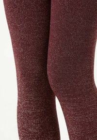 Burgundowe legginsy wykonane z błyszczącego, teksturowanego materiału, z błyszczącym wykończeniem i dopasowanym krojem, który podkreśla nogi.