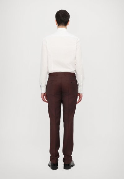 Chemise blanche à manches longues associée à un pantalon de costume bordeaux. La chemise a un col classique et le pantalon est ajusté avec des poches.