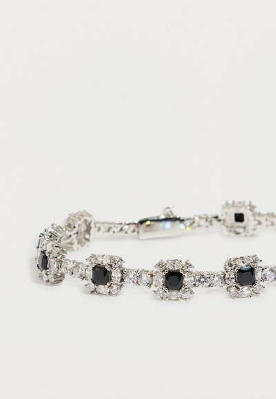 Ασημένιο βραχιόλι με εναλλασσόμενες μαύρες τετράγωνες και διαφανείς στρογγυλές πολύτιμες πέτρες, στερεωμένο με κούμπωμα σε λευκό φόντο.