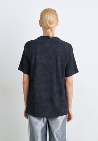 Zwarte, kort-hals T-shirt met een gestructureerd, gemarmerd effect. Heeft een ronde hals en een subtiel logo op de rug.