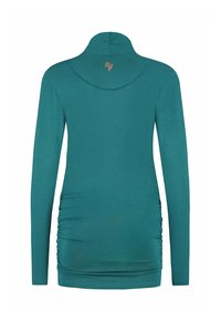 Teal långärmad turtleneck-topp med rynkade sidor och små beige broderade initialer nära kragen på baksidan.