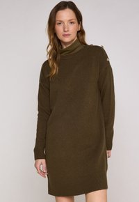 Abito a maglia verde oliva scuro con collo alto, polsini a coste e bottoni sulle spalle. Tessuto morbido con una vestibilità comoda.