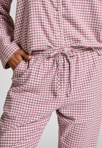 Ελαφρύ σετ πυτζάμας με καρό μοτίβο σε ροζ και λευκό. Περιλαμβάνει πουκάμισο με κουμπιά και ελαστική μέση με κορδόνι. Μαλακή υφή υφάσματος.