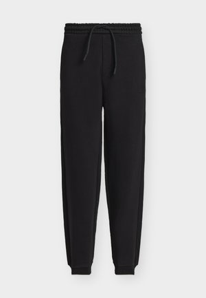 Sorte joggingbukser med elastisk talje, snøre, tilspidsede ben, manchetter ved anklerne og en lille lap på højre lår.