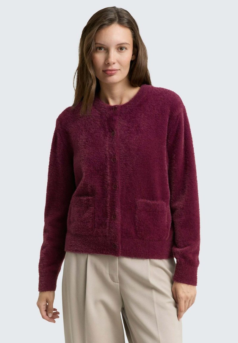 Bordeaux, fluffy cardigan met een ronde halslijn, voor knoopsluiting en twee opgestikte zakken op de taille. Zachte textuur, lange mouwen.