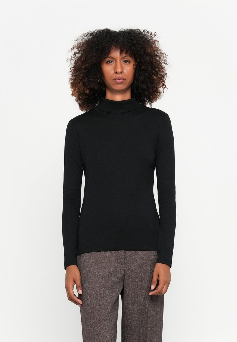 Schwarzes Langarm-Turtleneck aus weichem, elastischem Stoff, tailliertes Design. Tragen mit strukturierten, grauen, maßgeschneiderten Hosen.