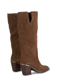 Bottes en suede marron, montantes jusqu'au genou, avec un design à rabat, un bout carré et un talon en bois texturé avec un détail en métal.