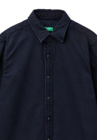 Granatowa koszula zapinana na guziki z klasycznym kołnierzem, czarnymi zatrzaskami i fakturowaną tkaniną z detalami szwów z przodu.