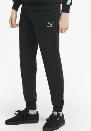 Schwarze Jogginghose aus weichem Stoff, mit schlanker Passform, gerippten Bündchen und einem weißen Puma-Logo am linken Oberschenkel.
