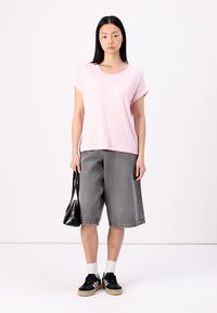 En rosa og hvit stripete t-skjorte med korte ermer, kombinert med grå denimshorts. Svart håndveske og svarte sneakers med lyse såler.