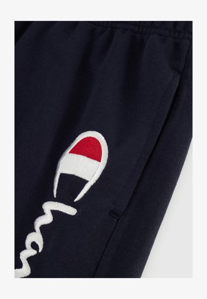 Pantaloni della tuta blu navy con logo ricamato bianco e accento rosso e bianco. Tessuto morbido, vita elasticizzata e tasche laterali.