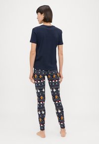 Camisa de manga corta navy combinada con leggings estampados en azul oscuro, que presentan coloridos motivos navideños como muñecos de nieve y casas de jengibre.