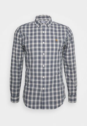 Chemise à manches longues boutonnée avec motif à carreaux bleu marine et blanc, col boutonné et petit logo brodé sur la poitrine.