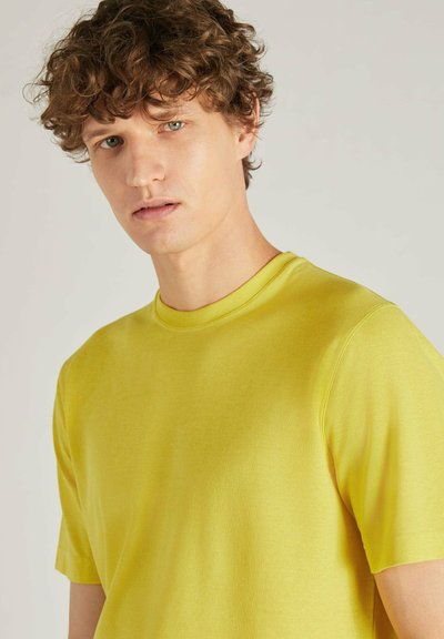 Camiseta de manga corta y cuello redondo en algodón de color amarillo brillante, con una textura suave y detalles de diseño mínimos.