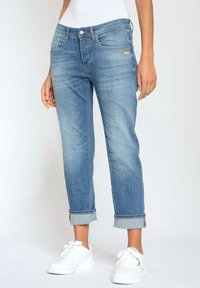 Ljust blå, raka denimjeans med blekt mönster, uppvikta fållar och metallknappslutning. Fram- och bakfickor synliga.