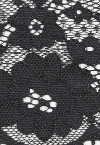 Tecido de renda preta com padrões florais, apresentando costura detalhada e uma textura de malha aberta. O design inclui formas variadas e espaços negativos.