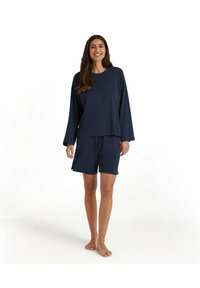 Navyblaues Loungewear-Set mit langärmligem Oberteil und passender Shorts. Weicher Stoff mit lockerer Passform und minimalen Nähdetails.