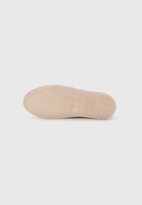 Semelle de chaussure en caoutchouc translucide avec des motifs texturés, comportant des rainures et de petits accents surélevés pour une meilleure adhérence et un soutien optimal. Couleur beige clair.