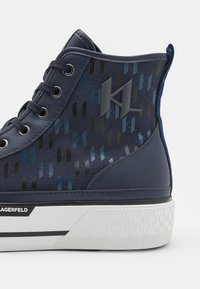 Visoke športne čevlje v mornarsko modri tkanini z geometrijskim vzorcem v temno modri in črni barvi. Imajo belo gumirano podplat in detajle z logotipom.