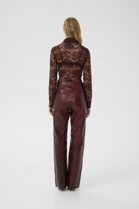 Bordeaux kanten blouse met lange mouwen gecombineerd met hoog getailleerde, gestructureerde nep leren broek met een krokodillenpatroon en een glanzende afwerking.