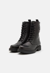 Bottes basses en cuir noir avec un design à lacets, un bout arrondi et un talon carré robuste. Elles disposent d'une languette à l'arrière et d'une texture lisse.