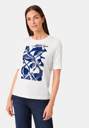 Weißes T-Shirt mit kurzen Ärmeln, das ein blaues und grünes abstraktes Muster hat, das auf der Vorderseite zentriert ist, mit dem Textüberlagerung "MAKE" und "AMAZING".