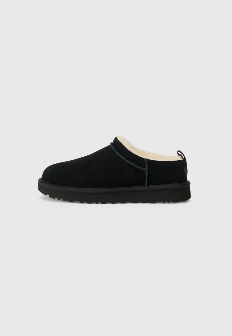 Svarte semskede slip-on sko med et mykt beige interiør, rund tå og strukturert gummisåle. Minimalistisk design med subtile sømmer.