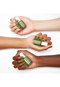 Drie handen tonen groene nagellak met een glanzende afwerking, terwijl ze een Essie-fles vasthouden. De nagelkleur varieert in schakeringen van groen op verschillende huidtinten.