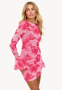 Vestido mini de manga larga bordado con flores en tono rosa, con una silueta ajustada, mangas acampanadas y detalles texturizados, que presenta llamativos patrones de flores rojas.